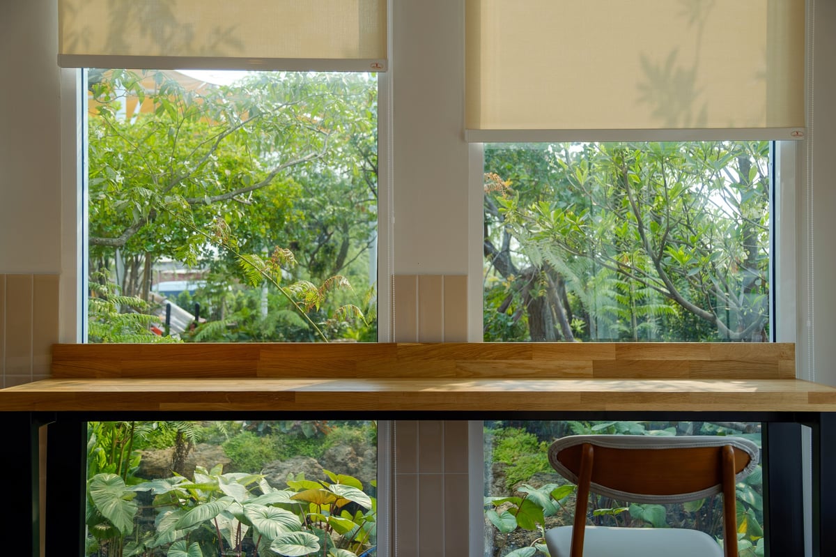 Minimalist wooden desk facing large windows with a green garden view