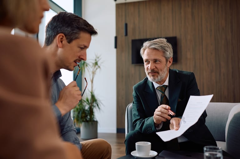Asesor financiero explicando a una pareja el cálculo de su finiquito o liquidación laboral en una oficina