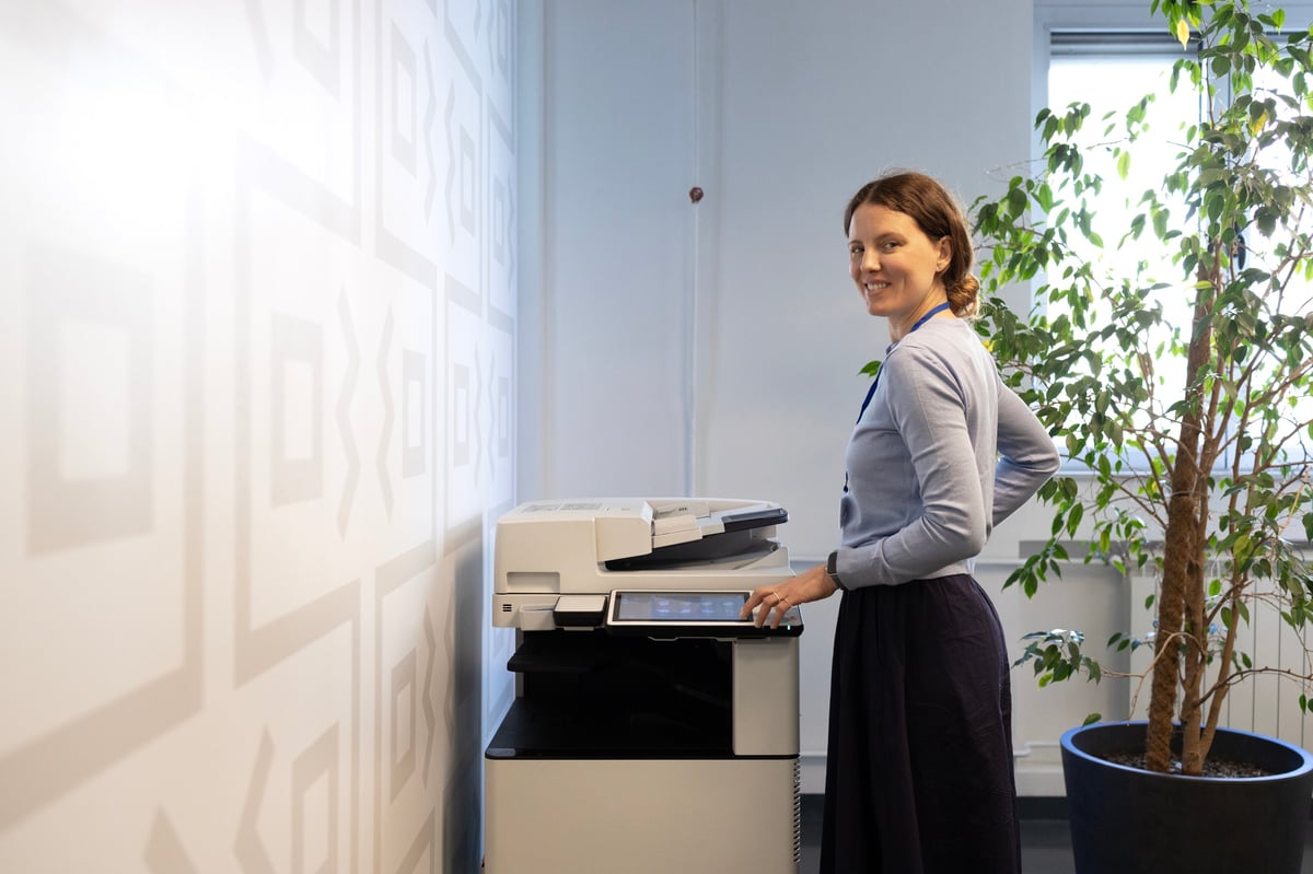 Businesswoman using a multifunction office printer in a bright modern Slough workspace