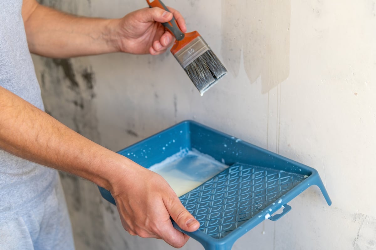 Miro Build construction company flyer showcasing drywall finishing, machine and hand plastering, sanding, and painting services with worker photos and contact number.