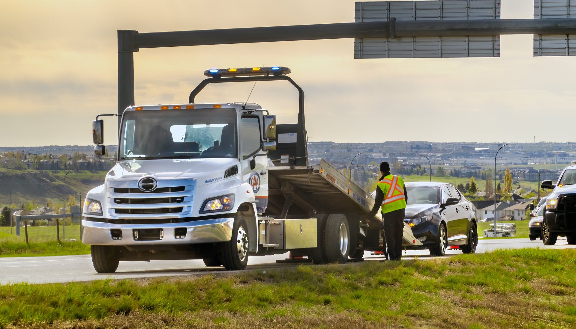 K&L Towing truck assisting a broken-down sedan on a highway