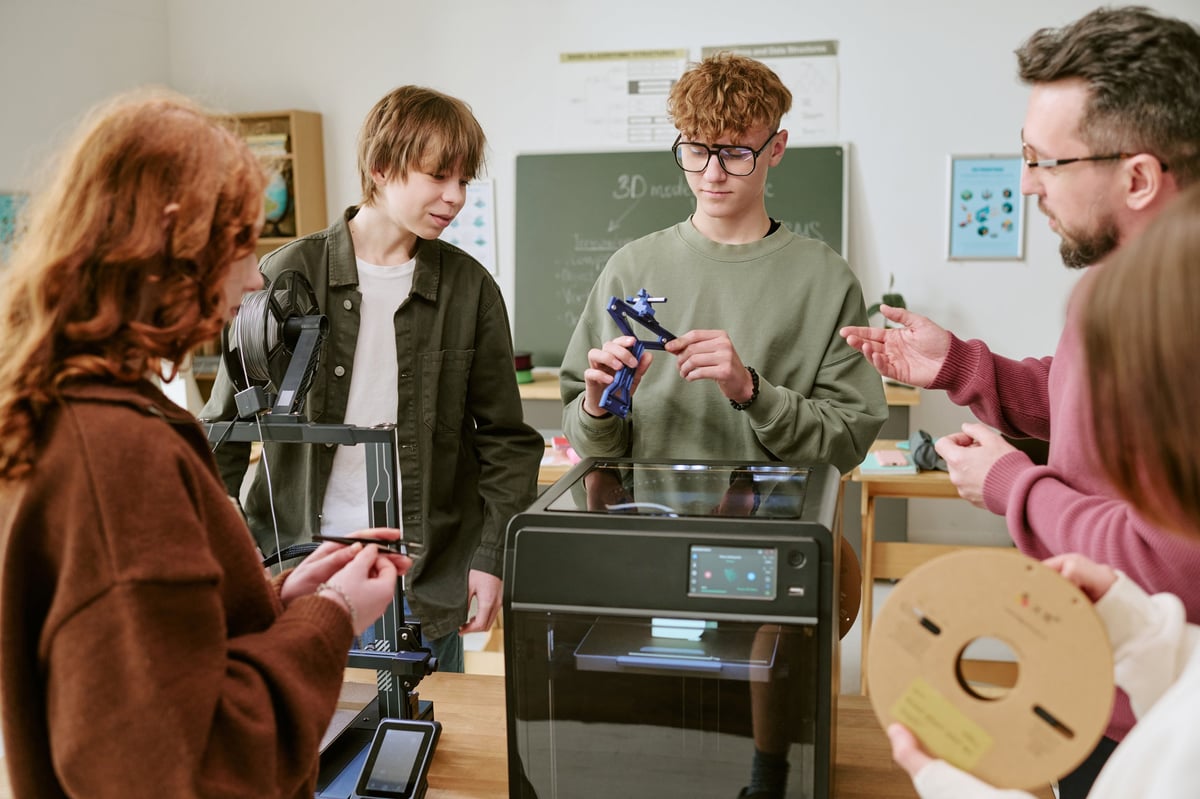 Professor orientando alunos em aula STEM com modelo 3D