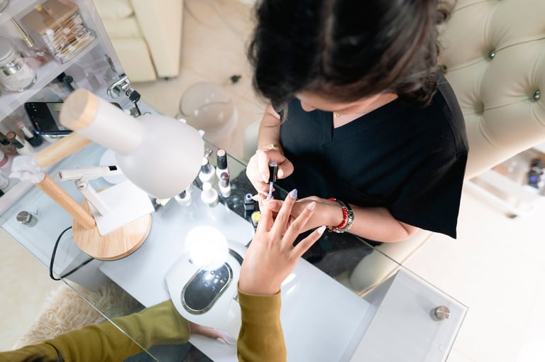 Beautician applying nail polish to client's fingernails at a beauty salon
