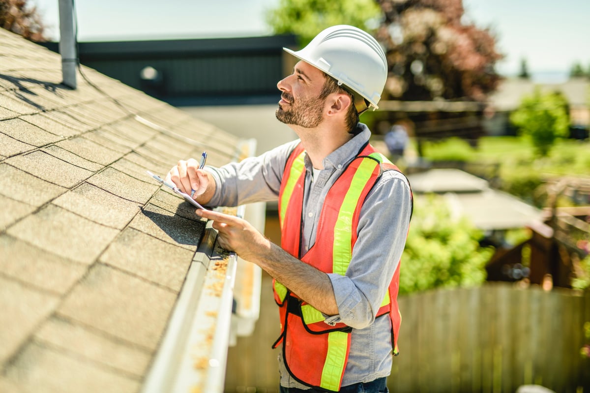 Property inspector in hard hat reviewing a building with a clipboard
