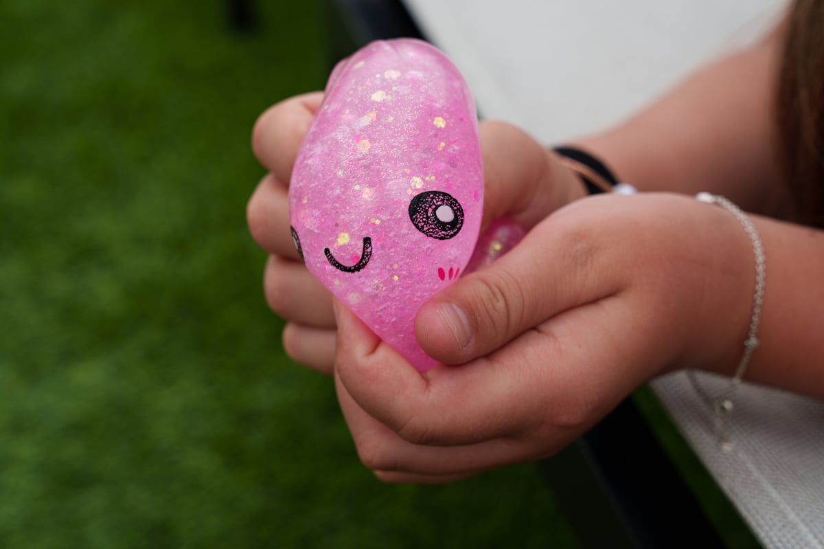 A child's hand squeezing a pink glitter squishy