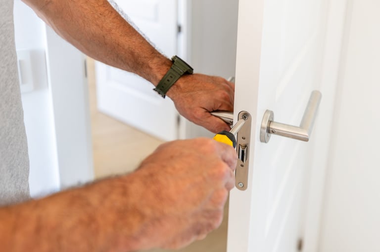 Man's hands installing a new door handle with a screwdriver during home repair