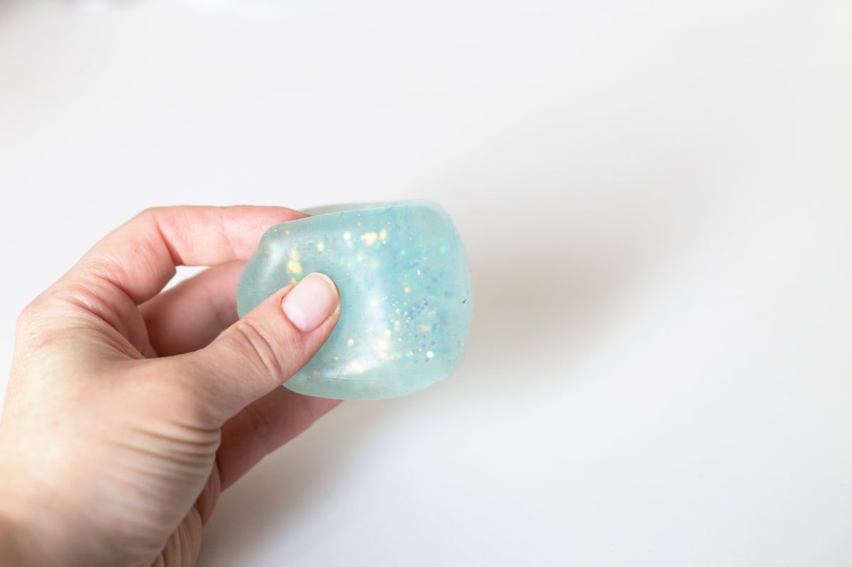 A blue glitter squishy toy being squished