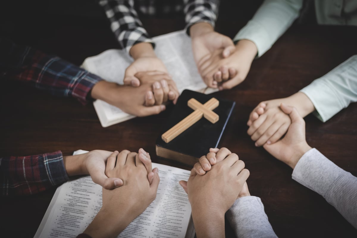 Group prayer and Bible fellowship with hands joined together