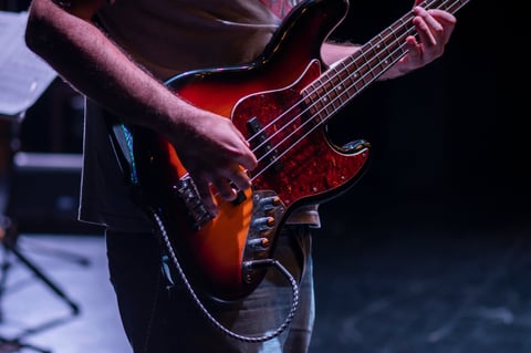 Baixista tocando durante show ao vivo sob iluminação de palco dramática