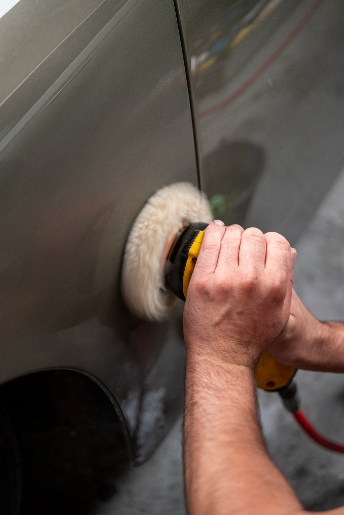 Paint correction close-up — restoring a car's paint with a rotary polisher