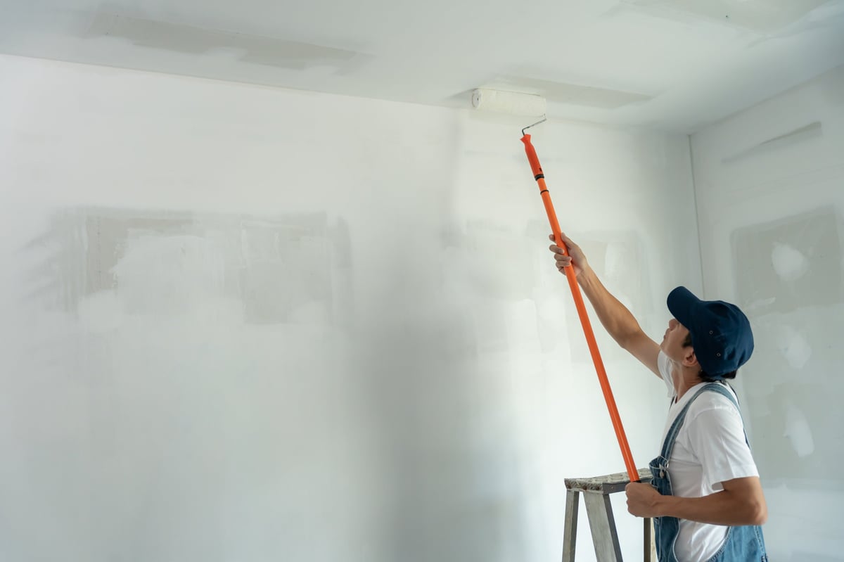 Painter with a brush working on a wall during renovation
