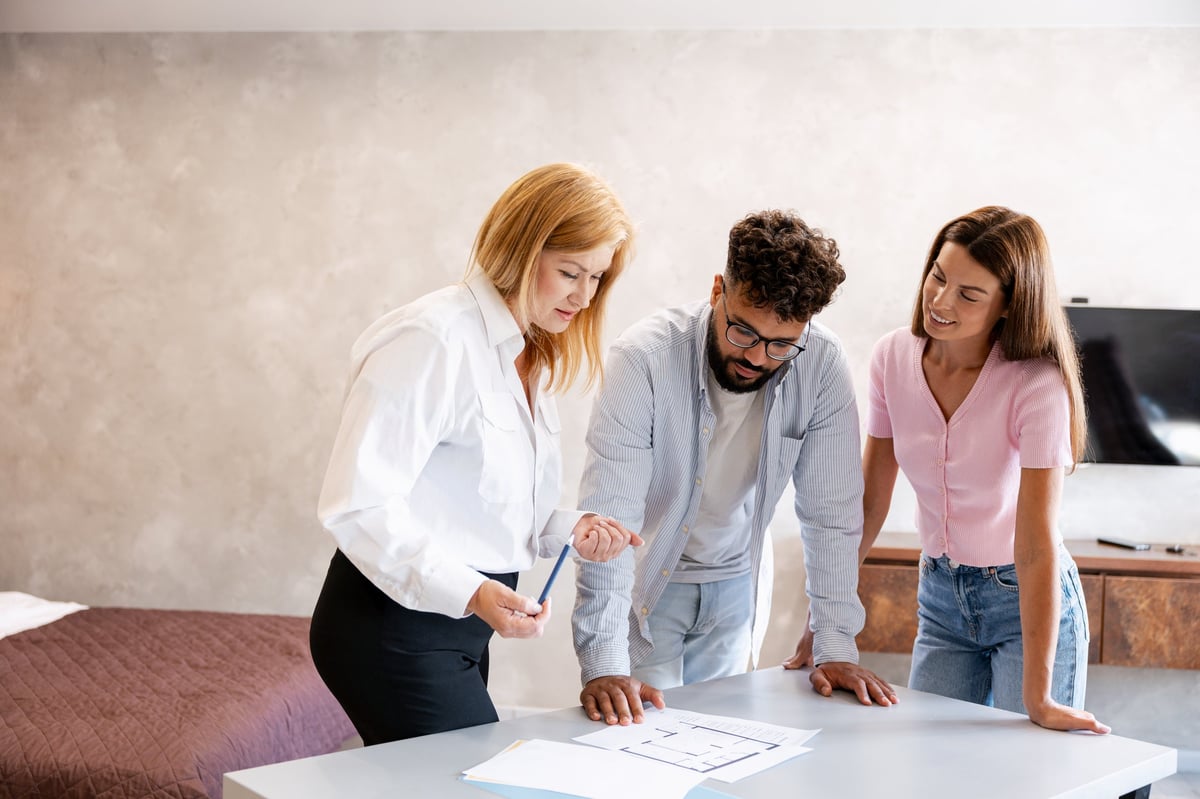 Real estate agent discussing home floor plans and property details with a young adult couple