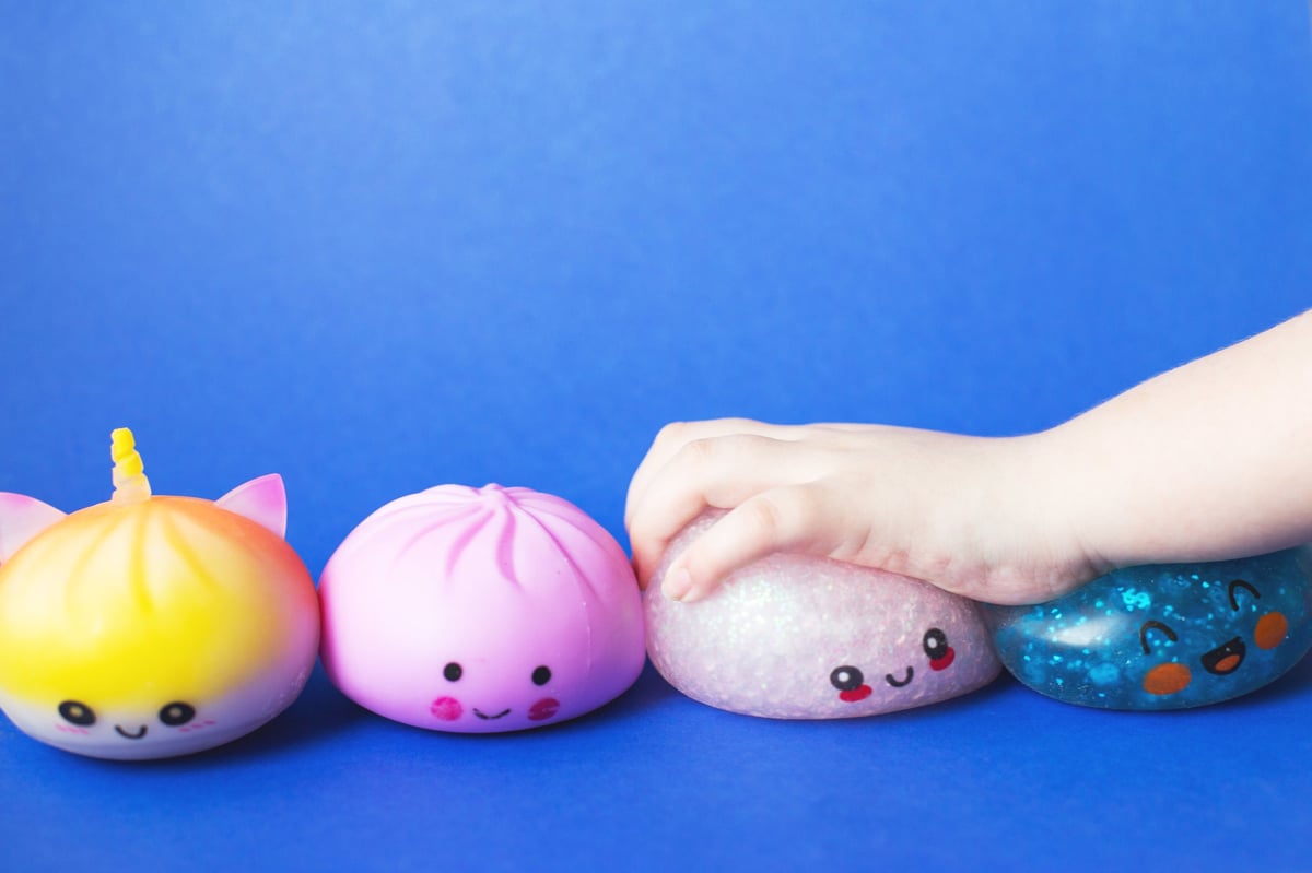 A child's hand squeezing cute squishy toys