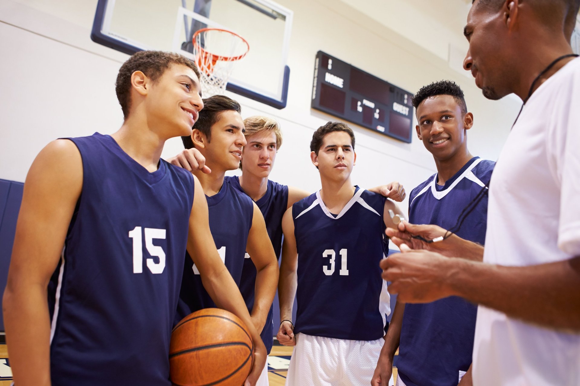 Lighthouse Athletics basketball team gathered in a huddle with their coach before a game