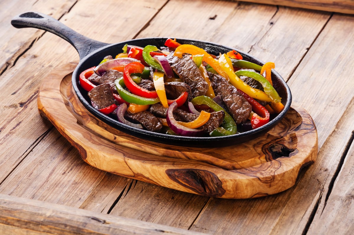 Beef fajitas with colorful bell peppers in cast iron pan