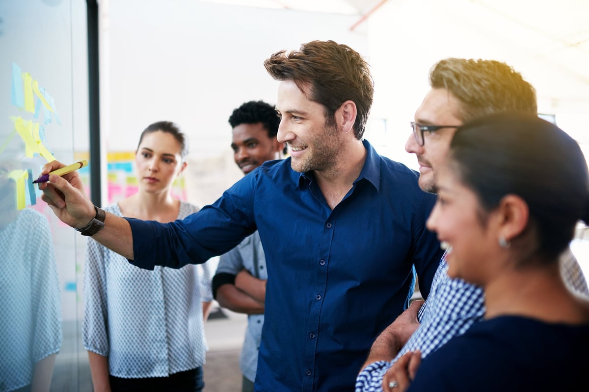 Team brainstorming together on a glass wall with sticky notes during a strategy session