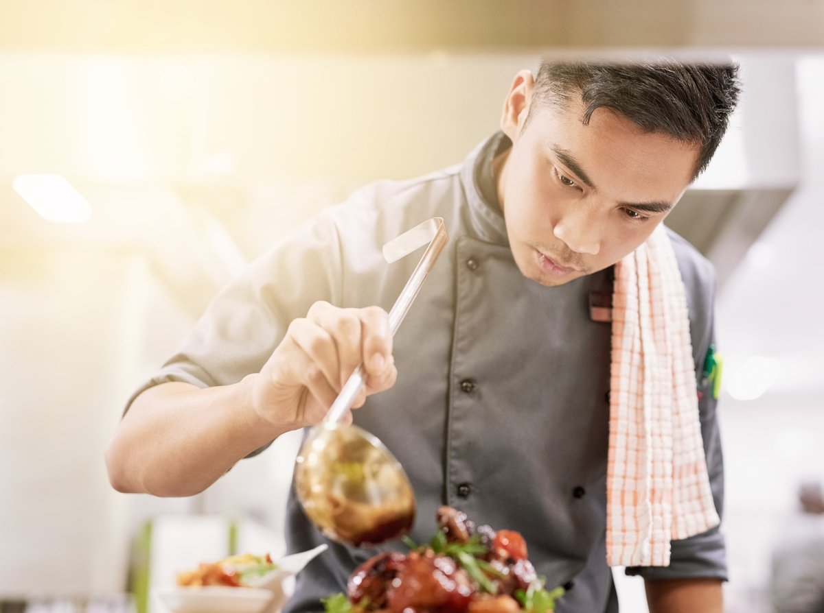 Young male chef cooking in his kitchen with Caribbean style