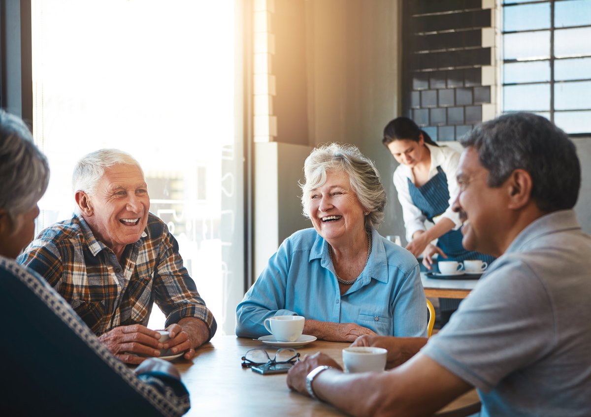 Active senior couples enjoying social time together at a cafe in an independent living community