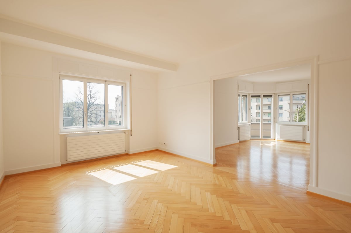 Lys tom leilighet med store vinduer og tregulv, klar for overlevering
