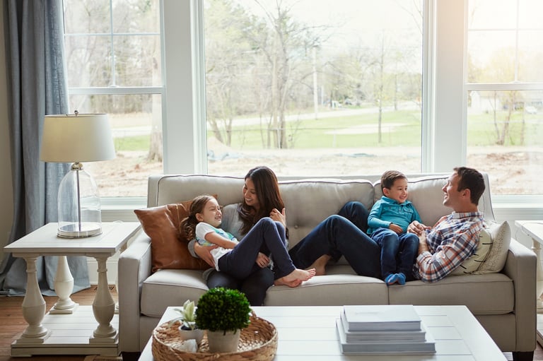 Happy young family of four relaxing together on the sofa at home