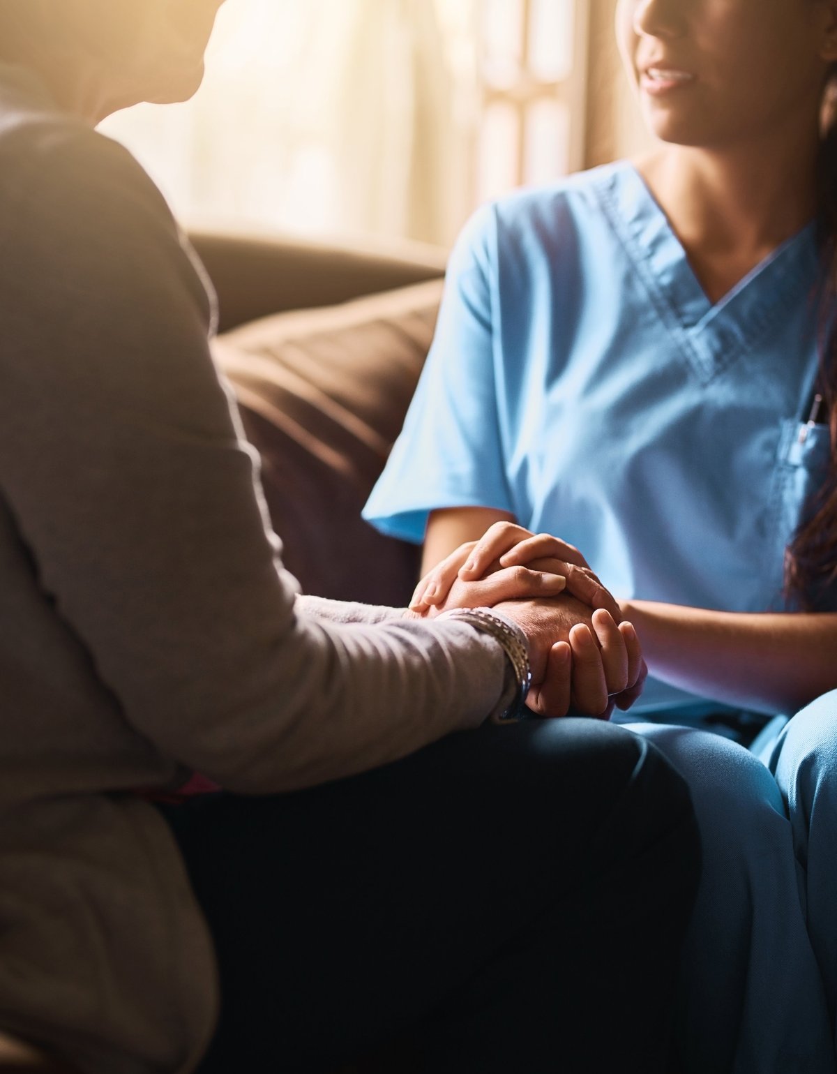 Nurse holding a senior woman's hands in comfort
