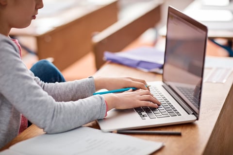 Elementary student working at a laptop with concentration and care