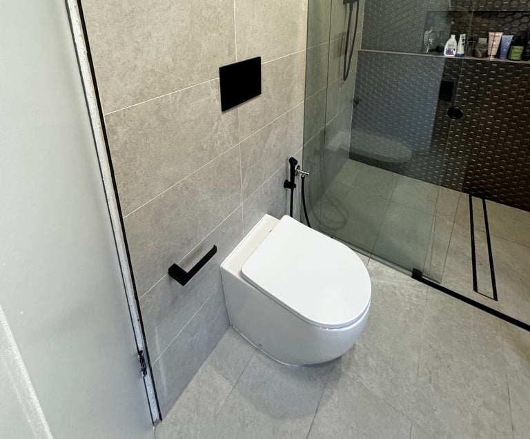 Modern bathroom with wall-mounted white toilet, glass shower enclosure, and gray tile flooring