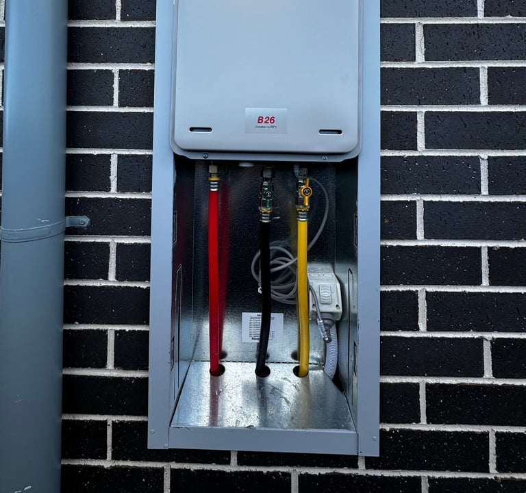 Electrical meter box mounted on black brick wall with red and yellow cables inside