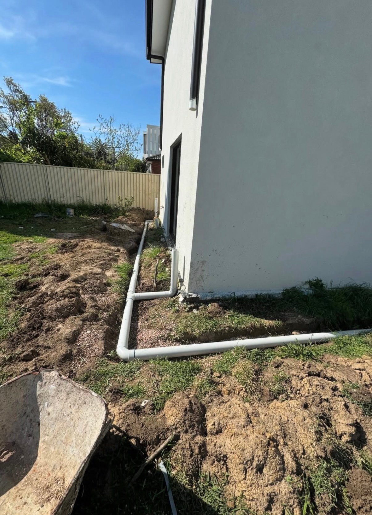 White downpipe and gutter system on corner of modern house during a plumbing maintenance job