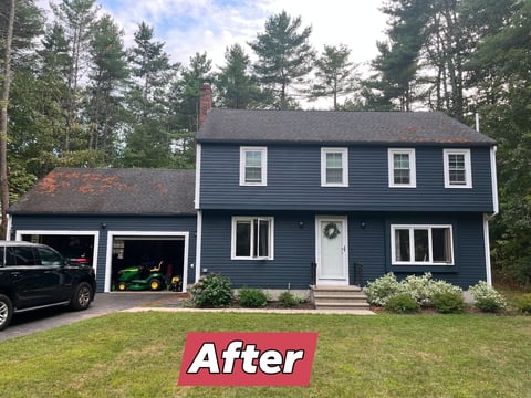 After: Renovated two-story blue house with white trim, attached garage, and manicured lawn surrounded by trees