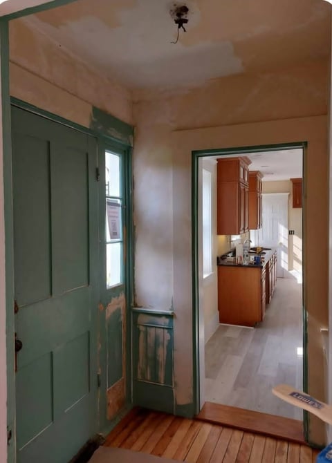 Before: Home entryway with green door on left, view into kitchen with wood cabinets on right