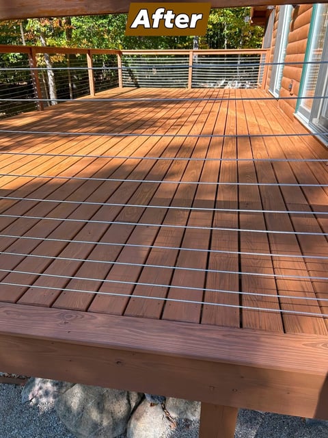 After: Newly refinished wooden deck with horizontal metal railing and forest view in background
