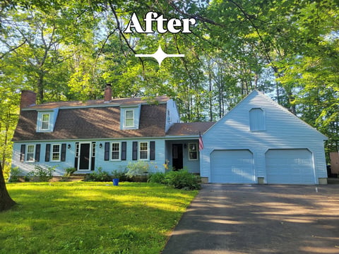 After: Two-story light blue house with garage surrounded by green lawn and trees