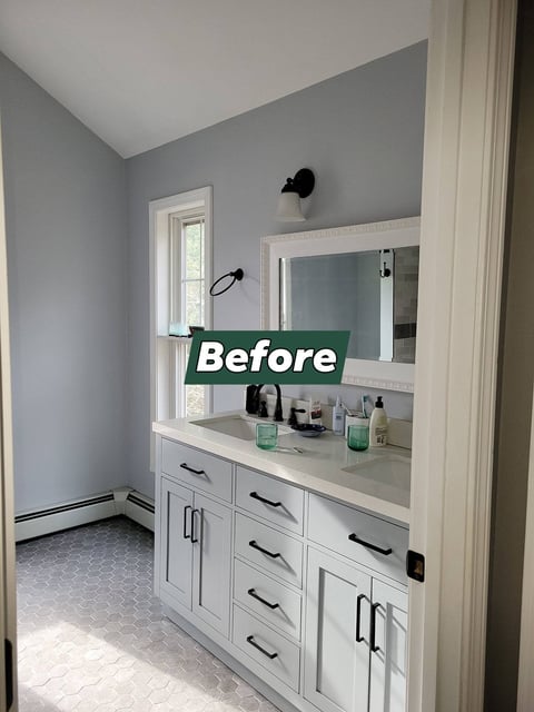 Before: Bathroom vanity with white cabinets, sink, and mirror against gray walls with window
