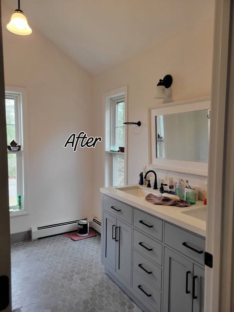 After: Modern bathroom after renovation with white cabinetry, framed mirror, black fixtures, and hexagonal tile flooring