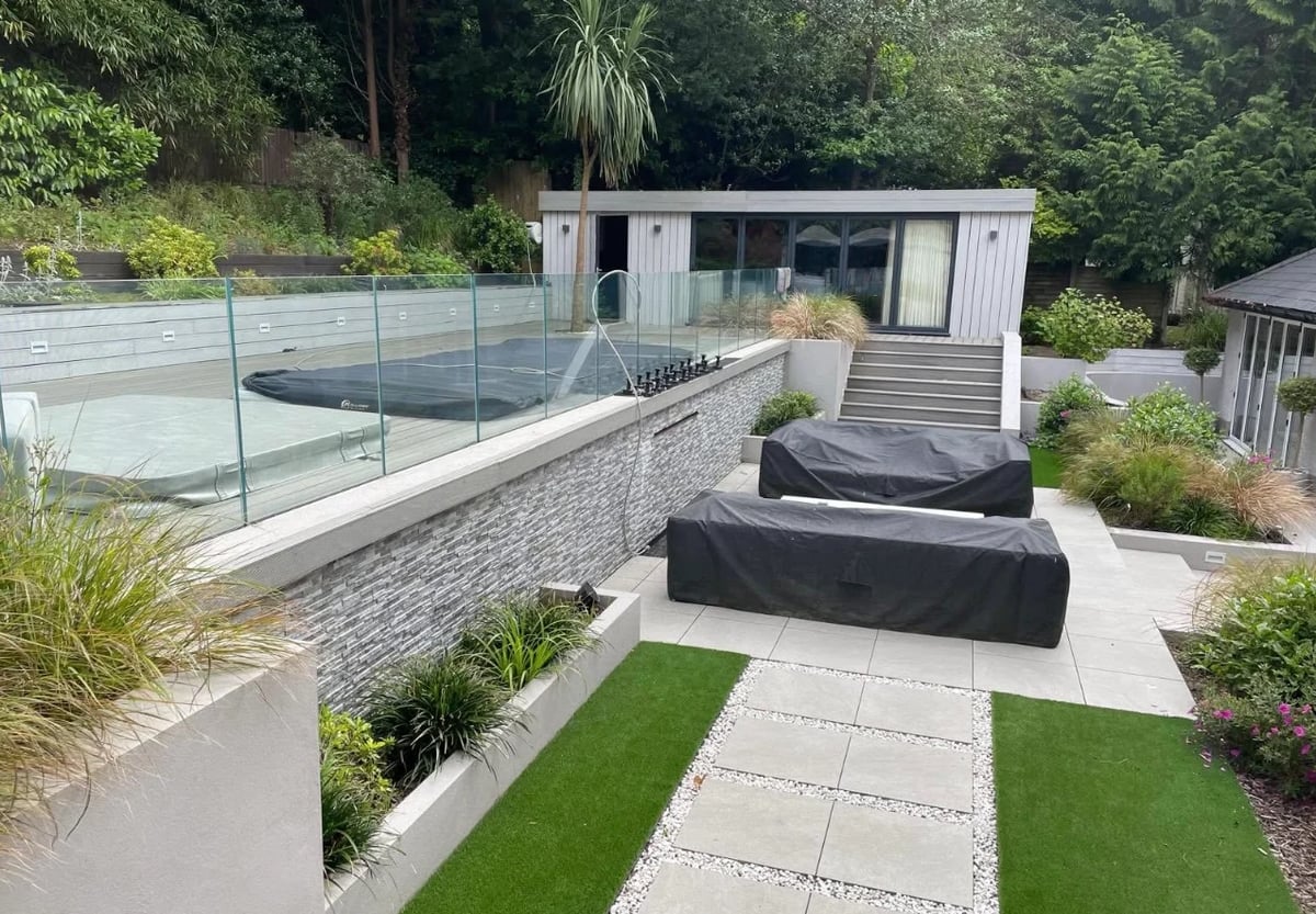 After: twin garden rooms with raised decking between them, brick walls, stairs on both sides, and a patio below