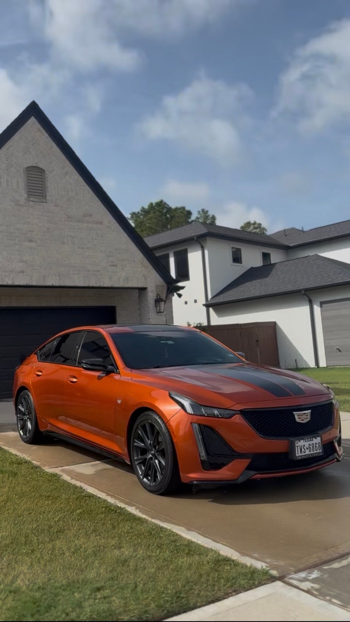 KJAJ Details finished detail — bright orange Cadillac CT4 sedan with deep gloss parked in a residential driveway