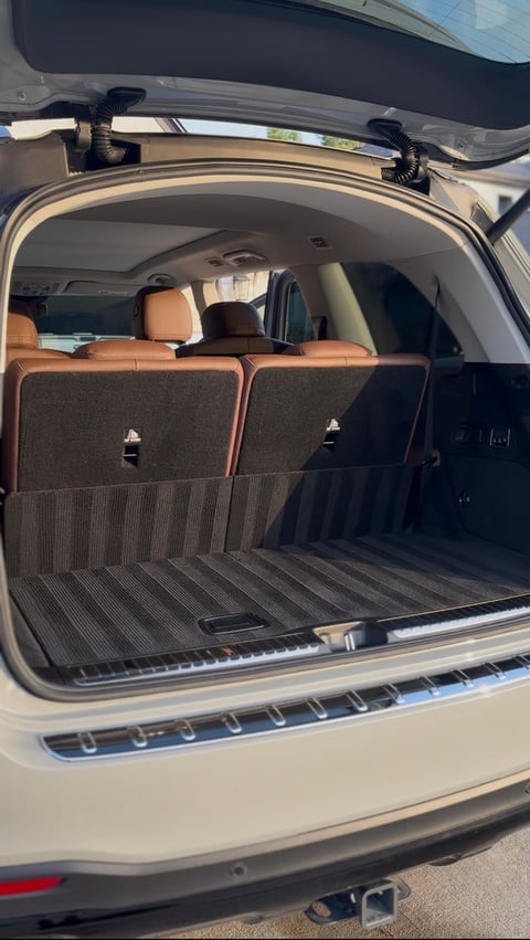 Open cargo area of a white SUV with leather seats visible, roof rack crossbars, and lined trunk bed — KJAJ Details cargo detail