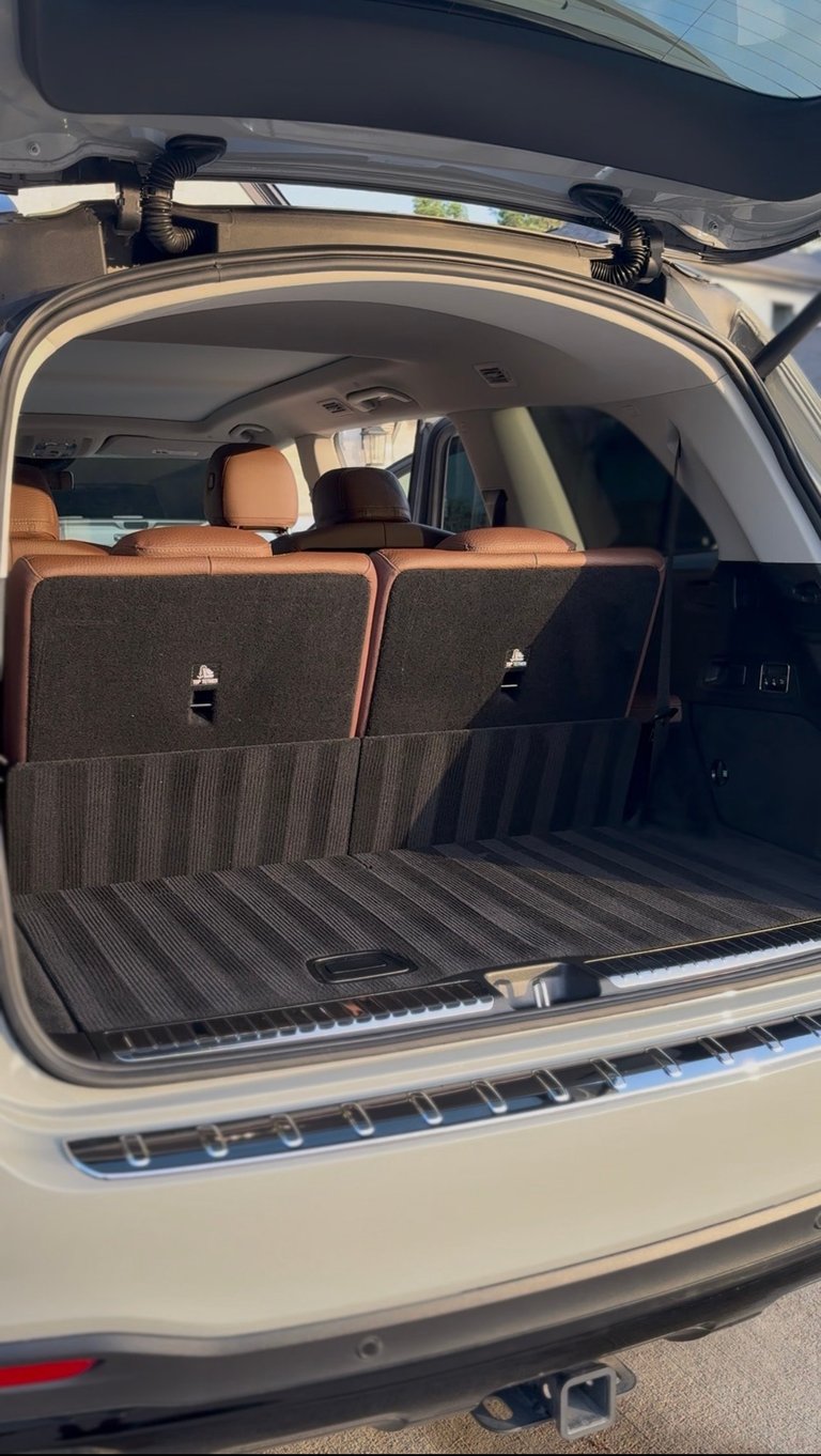 Open cargo area of a white SUV with leather seats visible, roof rack crossbars, and lined trunk bed — KJAJ Details cargo detail