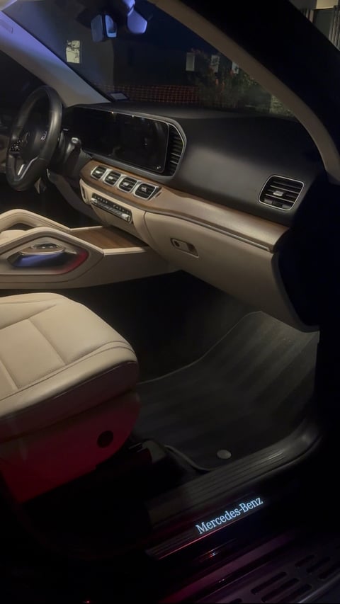 Mercedes-Benz luxury interior showing leather seats, dashboard with touchscreen display, and illuminated door sill at night