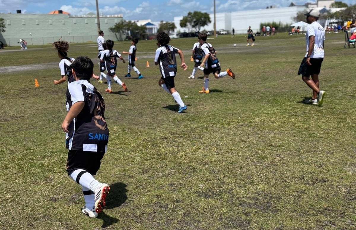 Youth soccer players in black and white uniforms running during an outdoor game on a grass field