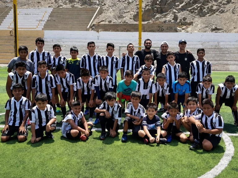 Youth soccer team in black and white striped uniforms posing together on a grass field