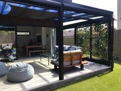 Modern backyard patio with black pergola, outdoor seating area and lush green lawn