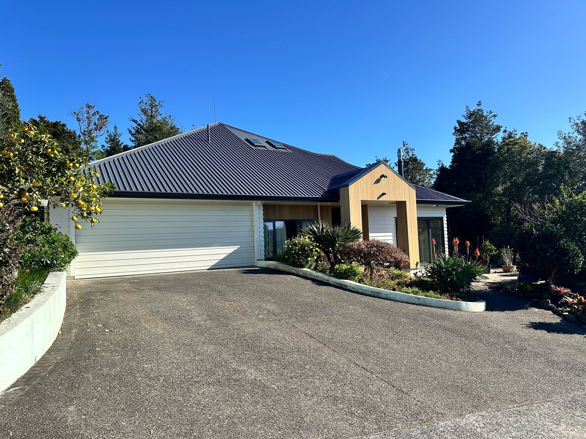 Completed cream and black reclad North Shore home with dark metal roof and landscaped garden