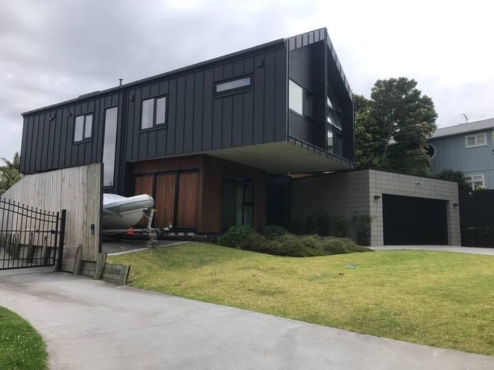 Modern black and white residential house with geometric design, concrete driveway and manicured lawn