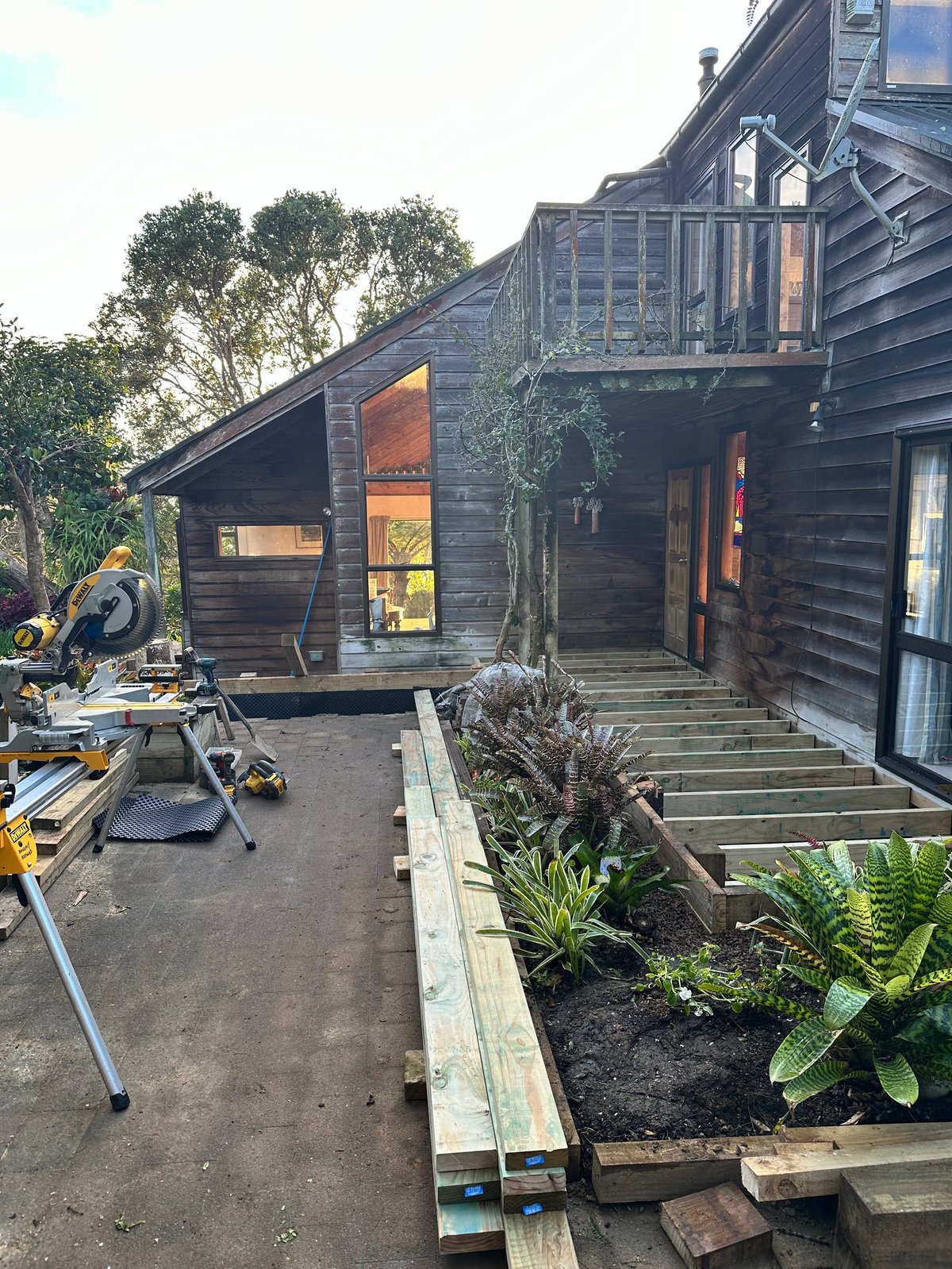 West Auckland home renovation with new deck and cladding, set amongst trees