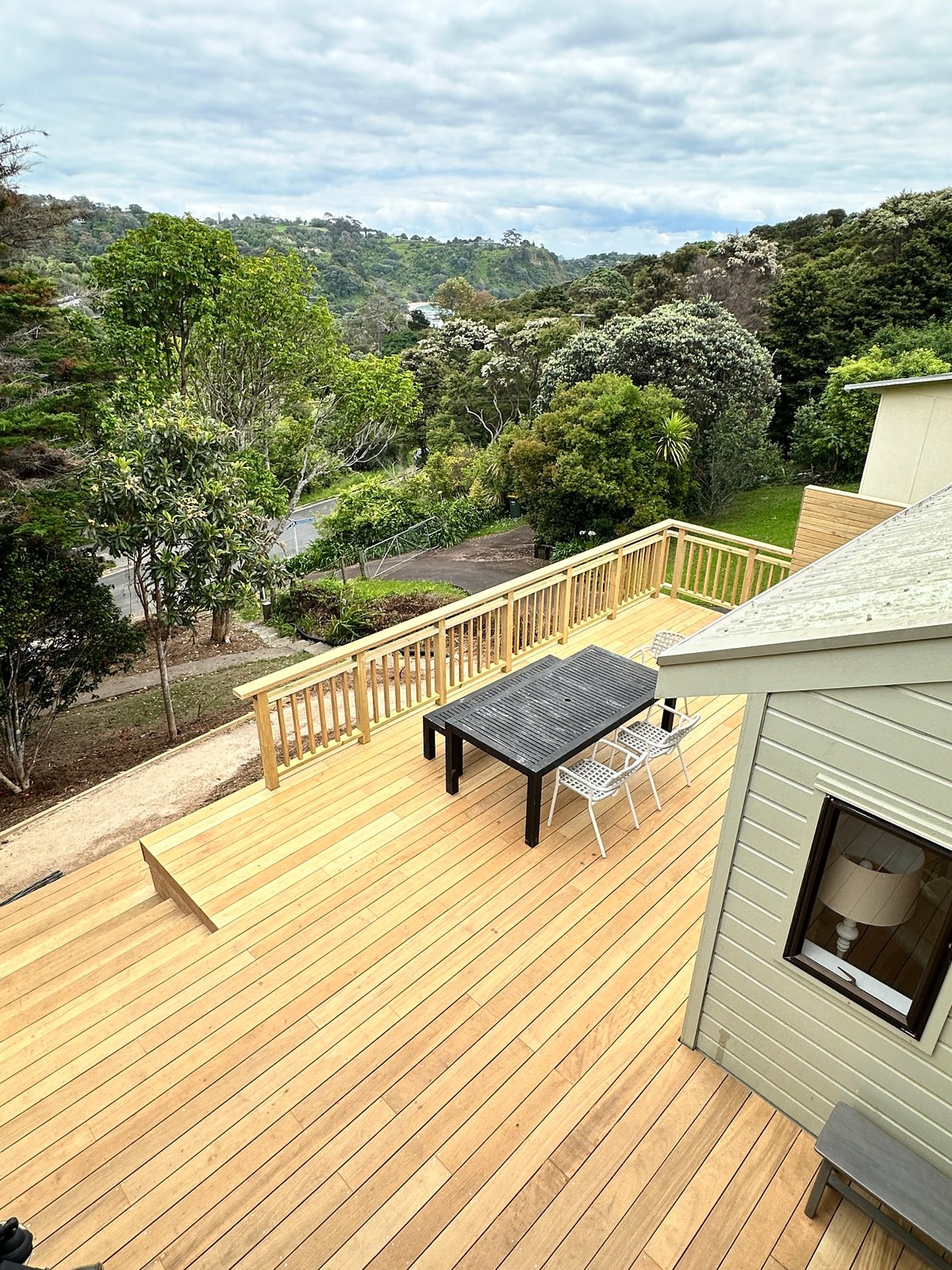 Wooden deck with dining table overlooking forested valley and winding river below