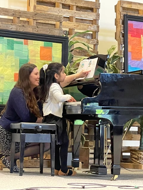 Two students at piano reading sheet music during lesson