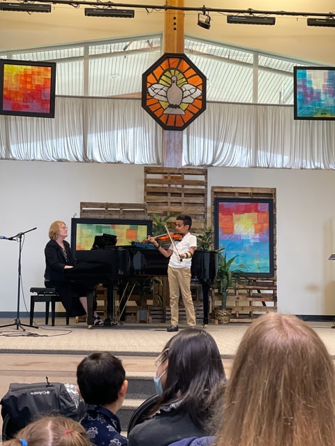Young violinist performing with pianist on stage