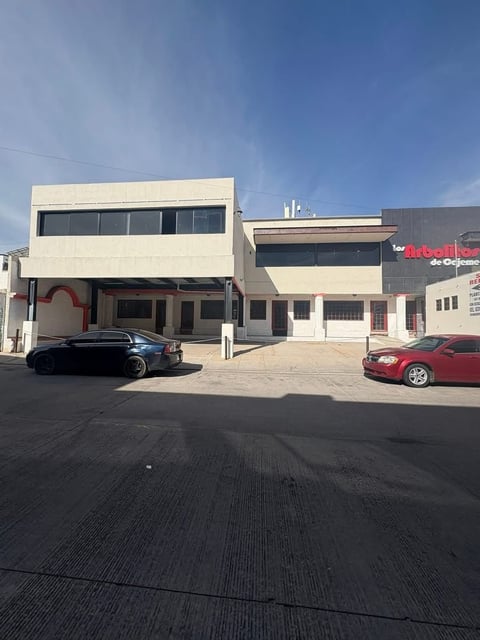 Fachada de edificios comerciales modernos con locales y estacionamiento bajo cielo azul
